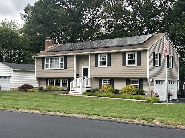 305 Rambler St, Bristol, CT 06010 - bi-level home featuring solar panels, a chimney, a front yard, and an attached garage