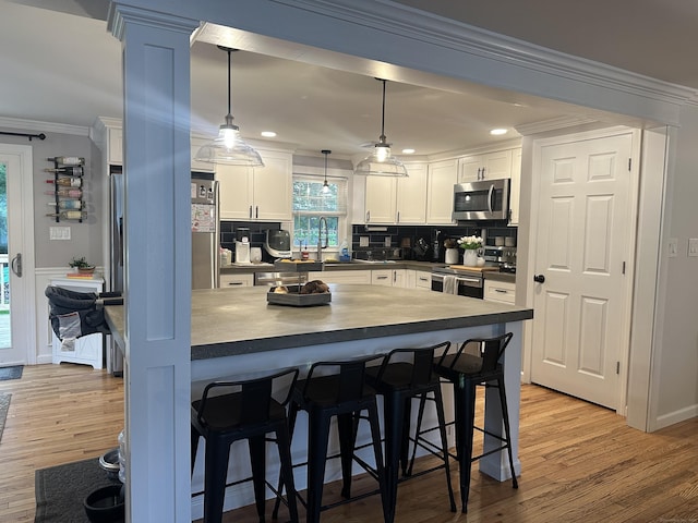 305 Rambler St, Bristol, CT 06010 - kitchen featuring appliances with stainless steel finishes, a breakfast bar area, crown molding, dark countertops, and white cabinets