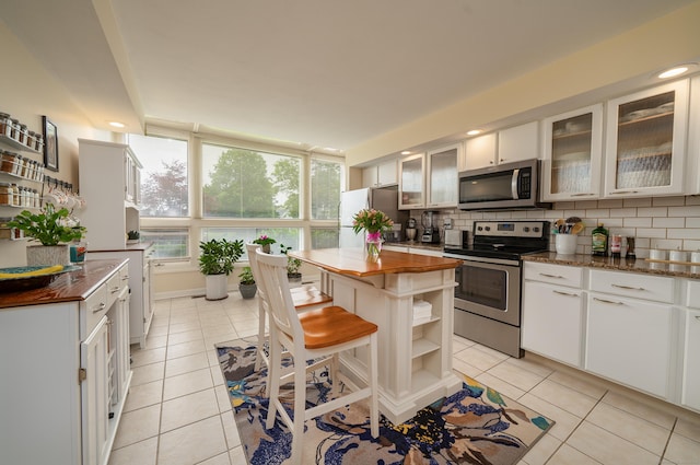 170 Turtle Bay Dr Unit 170, Branford, CT 06405 - kitchen with appliances with stainless steel finishes, butcher block countertops, tasteful backsplash, light tile patterned floors, and open shelves