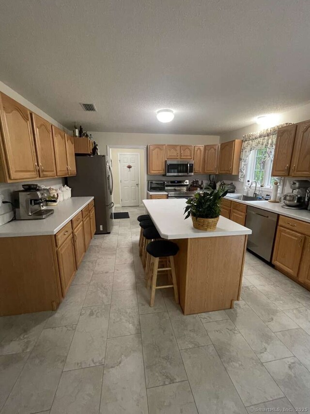 475 Niederwerfer Rd, South Windsor, CT 06074 - kitchen featuring stainless steel appliances, a center island, light countertops, a breakfast bar, and a textured ceiling