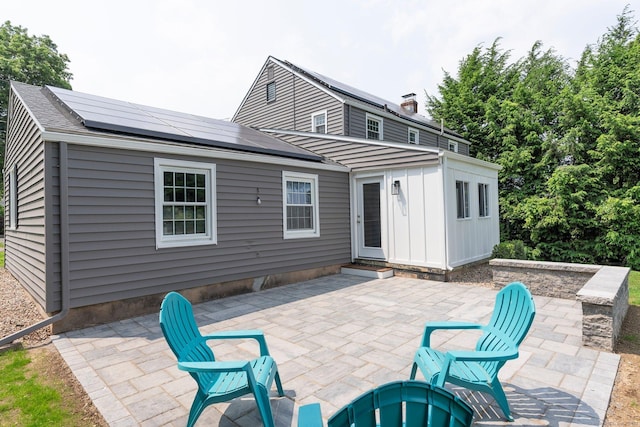 114 Boulter Rd, Wethersfield, CT 06109 - back of property with a patio area, roof mounted solar panels, board and batten siding, and an outdoor fire pit