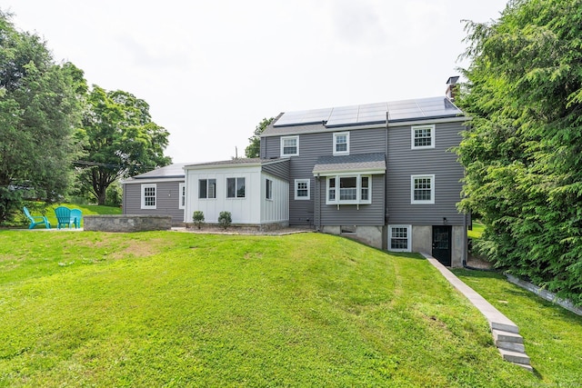 114 Boulter Rd, Wethersfield, CT 06109 - back of property with roof mounted solar panels, a lawn, board and batten siding, and a chimney