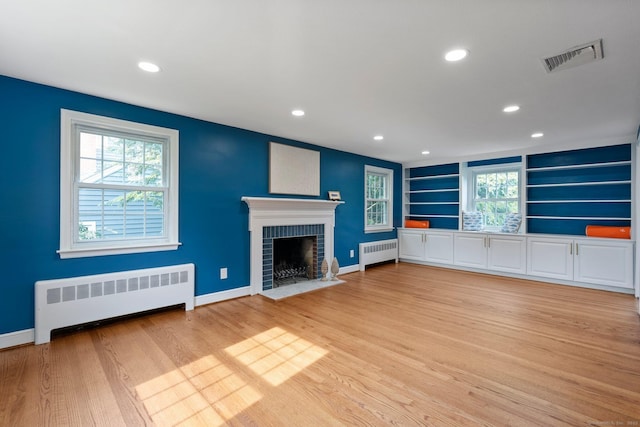 114 Boulter Rd, Wethersfield, CT 06109 - unfurnished living room with radiator heating unit, a brick fireplace, light wood-style flooring, recessed lighting, and built in features