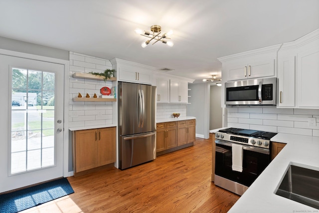 114 Boulter Rd, Wethersfield, CT 06109 - kitchen featuring stainless steel appliances, open shelves, light countertops, backsplash, and light wood finished floors