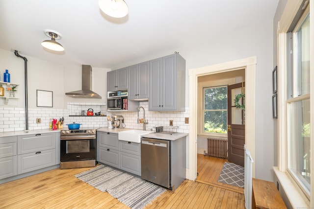 45 Harris Fuller Rd, Preston, CT 06365 - kitchen featuring stainless steel appliances, gray cabinetry, wall chimney exhaust hood, radiator, and light wood finished floors