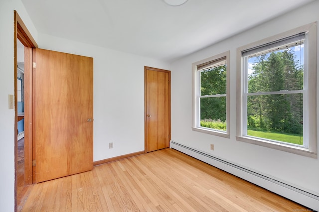 442 Merrow Rd, Tolland, CT 06084 - unfurnished bedroom with a baseboard radiator, multiple windows, and wood finished floors
