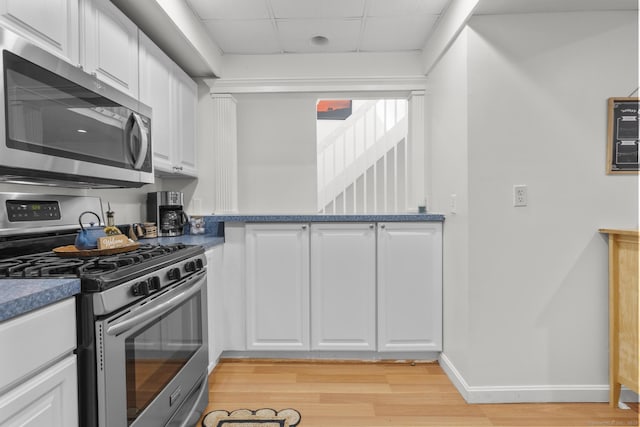 32 Glenview Dr Unit 32, Cromwell, CT 06416 - kitchen featuring stainless steel appliances, white cabinetry, light wood-style floors, a paneled ceiling, and dark countertops