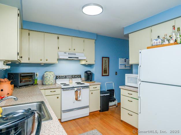 172 Old Farms Rd Unit 172, Torrington, CT 06790 - kitchen with white appliances, under cabinet range hood, light countertops, and light wood-style floors