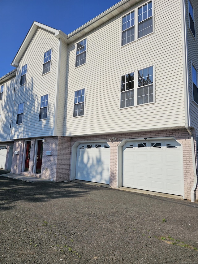 26 Roger Ave, Danbury, CT 06810 - rear view of house featuring an attached garage, brick siding, and driveway