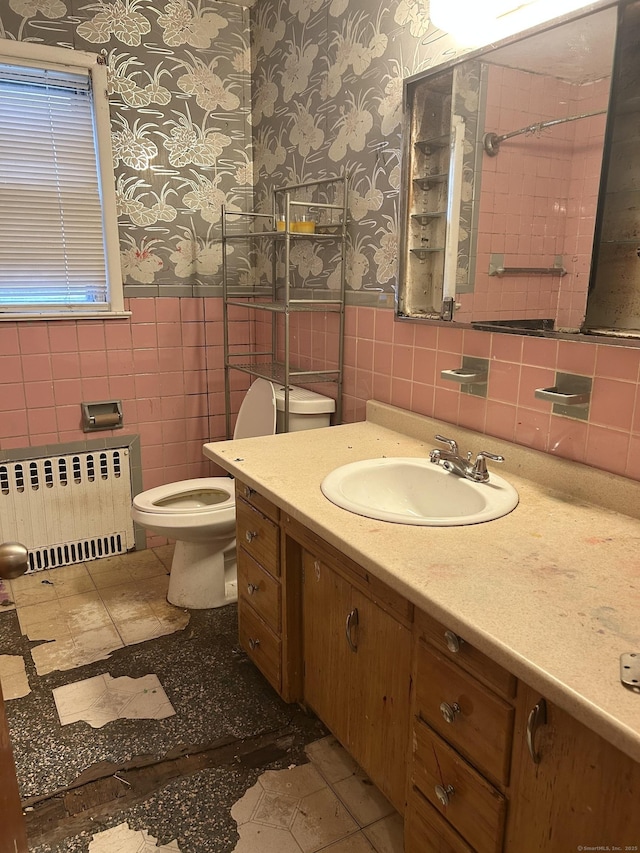71 Saddle Rd, Norwalk, CT 06851 - bathroom with radiator heating unit, wallpapered walls, tile walls, vanity, and wainscoting