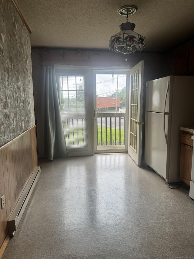 260 Scott Rd Apt 1, Waterbury, CT 06705 - unfurnished dining area featuring baseboard heating, a textured ceiling, a wainscoted wall, and wood walls