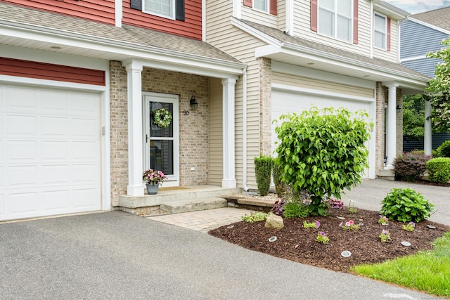90 Bridlewood Ln Unit 90, Vernon, CT 06066 - view of exterior entry with a garage, roof with shingles, asphalt driveway, and brick siding