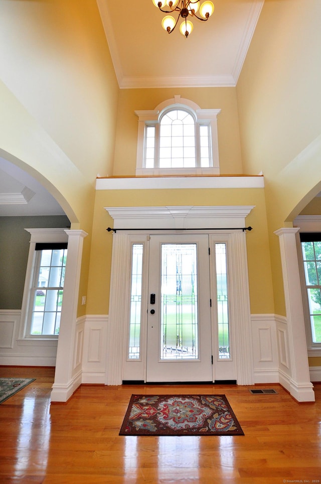 1 Leghorn Ln, Cromwell, CT 06416 - foyer entrance with arched walkways, ornate columns, wainscoting, wood finished floors, and a chandelier