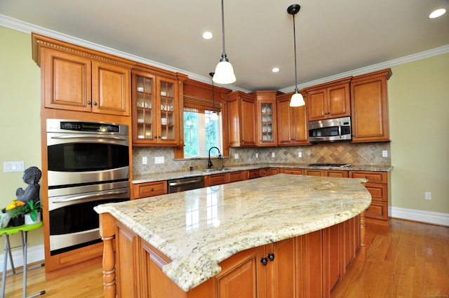 1 Leghorn Ln, Cromwell, CT 06416 - kitchen featuring appliances with stainless steel finishes, brown cabinets, light wood-style flooring, light stone counters, and a kitchen island