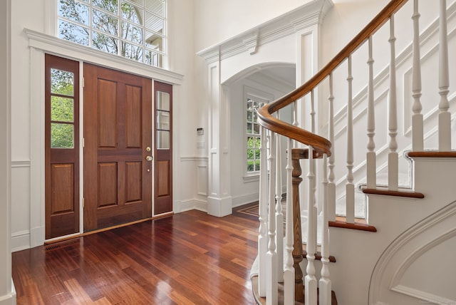 43 Chessor Ln, Wilton, CT 06897 - foyer entrance featuring wood finished floors, plenty of natural light, arched walkways, a decorative wall, and stairs