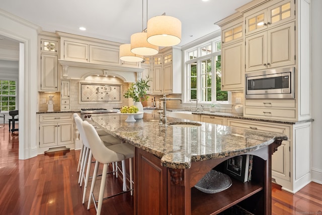 43 Chessor Ln, Wilton, CT 06897 - kitchen featuring open shelves, stainless steel microwave, cream cabinets, a kitchen island with sink, and recessed lighting