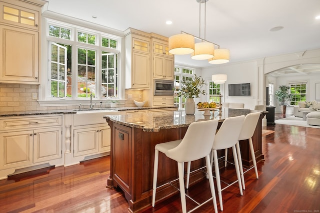 43 Chessor Ln, Wilton, CT 06897 - kitchen featuring stainless steel microwave, cream cabinets, dark wood-style floors, dark stone countertops, and plenty of natural light