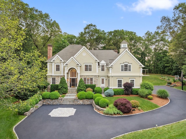 43 Chessor Ln, Wilton, CT 06897 - view of front of house featuring a chimney, stone siding, view of wooded area, and a front yard
