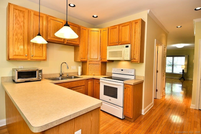 375 Allyn St Unit A4, Groton, CT 06355 - kitchen featuring white appliances, light countertops, light wood-type flooring, a peninsula, and hanging light fixtures