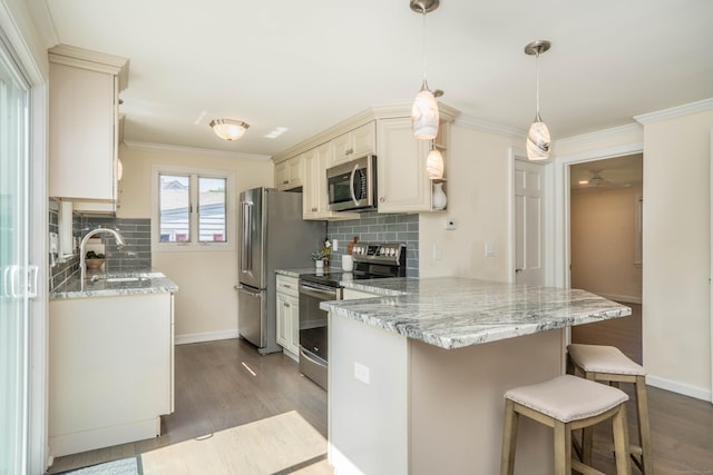 21 Walnut St, Newington, CT 06111 - kitchen featuring stainless steel appliances, a kitchen breakfast bar, a peninsula, cream cabinetry, and decorative backsplash
