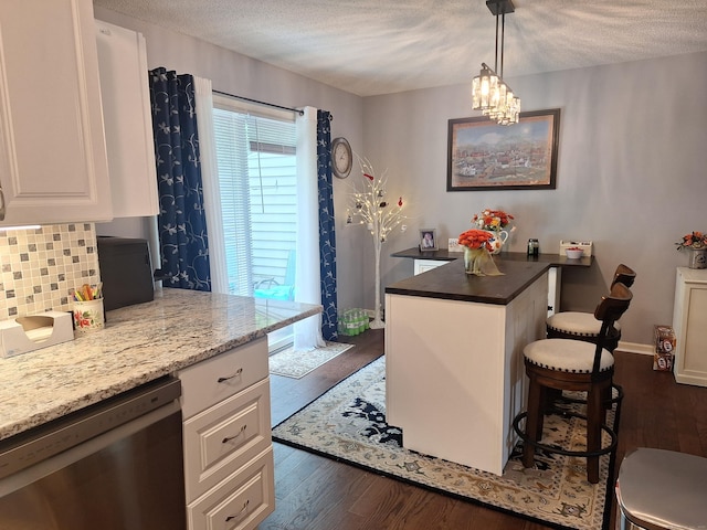 67 Fox Hollow Dr Unit 67, Windsor Locks, CT 06096 - kitchen with stainless steel dishwasher, a breakfast bar area, a textured ceiling, white cabinets, and dark wood-type flooring