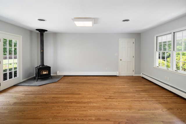 173 Russet Rd, Stamford, CT 06903 - unfurnished living room with a baseboard radiator, a wood stove, plenty of natural light, and light wood-style flooring