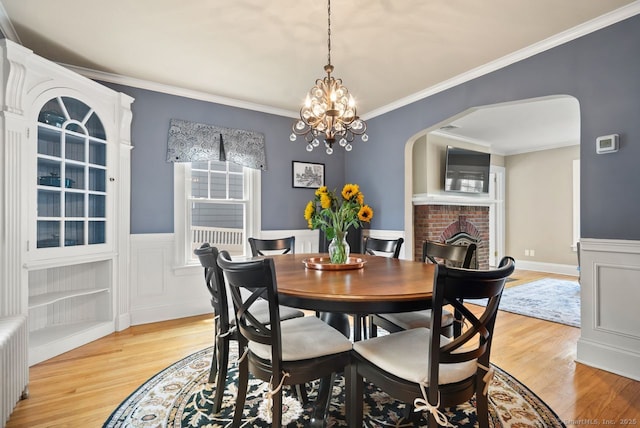 140 Griswold Dr, West Hartford, CT 06119 - dining area featuring arched walkways, light wood-style flooring, radiator heating unit, crown molding, and a chandelier