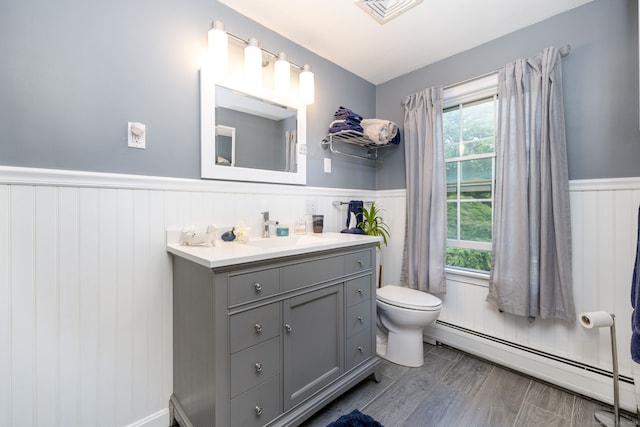 123 Silkey Rd, Granby, CT 06060 - half bath with a baseboard radiator, wainscoting, vanity, and wood finished floors
