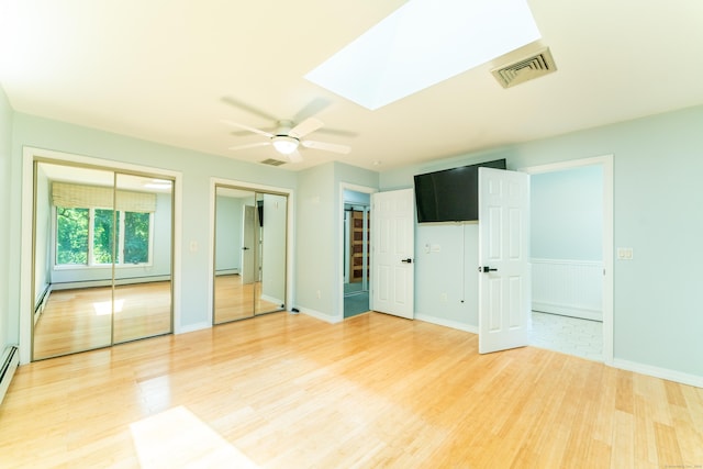 24 Newton St, Norwich, CT 06360 - unfurnished bedroom featuring light wood-style floors, multiple closets, a baseboard radiator, a skylight, and ceiling fan