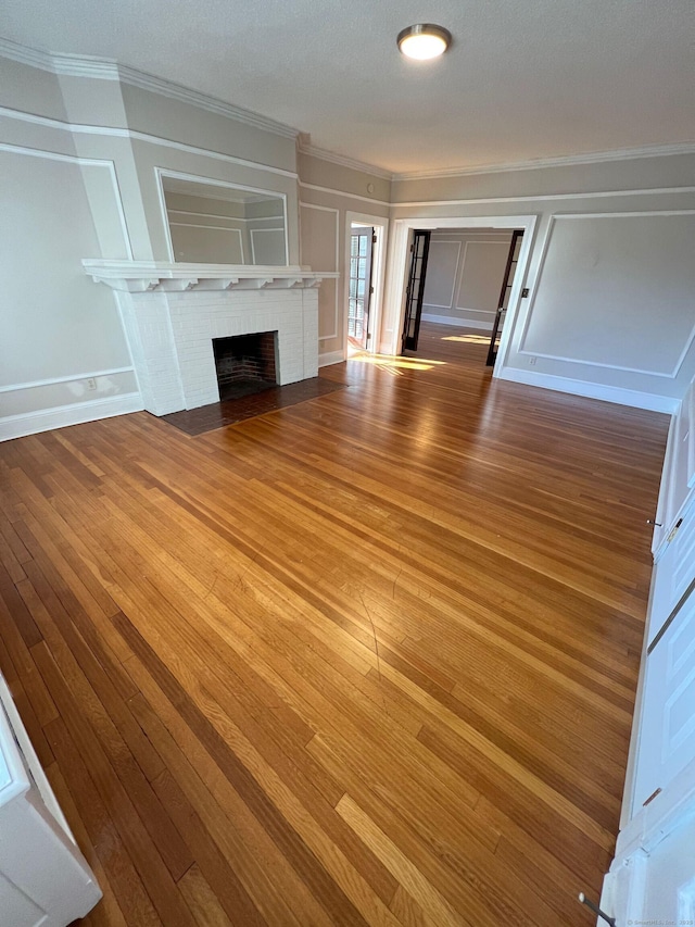 17 Maplewood Ave, West Hartford, CT 06119 - unfurnished living room with ornamental molding, a decorative wall, hardwood / wood-style flooring, and a fireplace