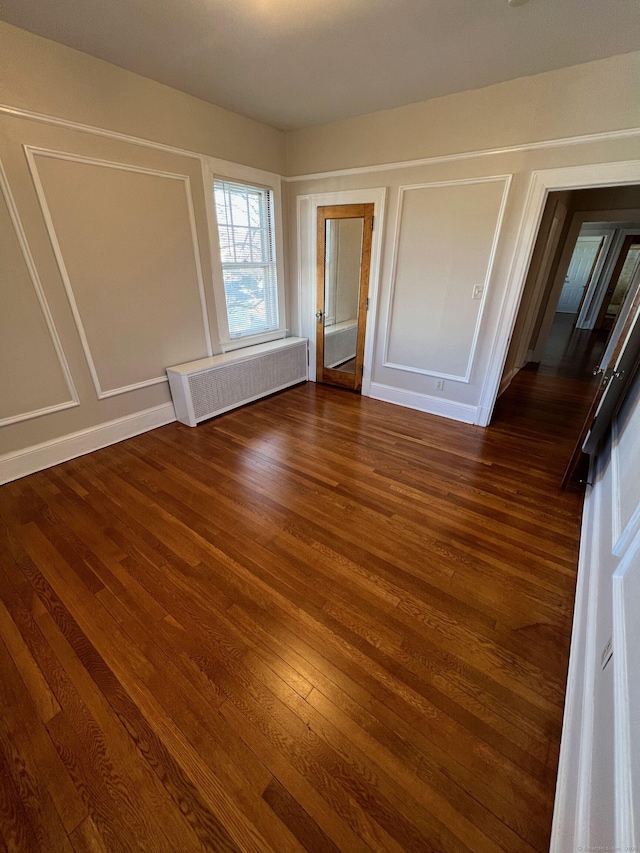 17 Maplewood Ave, West Hartford, CT 06119 - unfurnished bedroom featuring radiator heating unit, dark wood finished floors, and a decorative wall