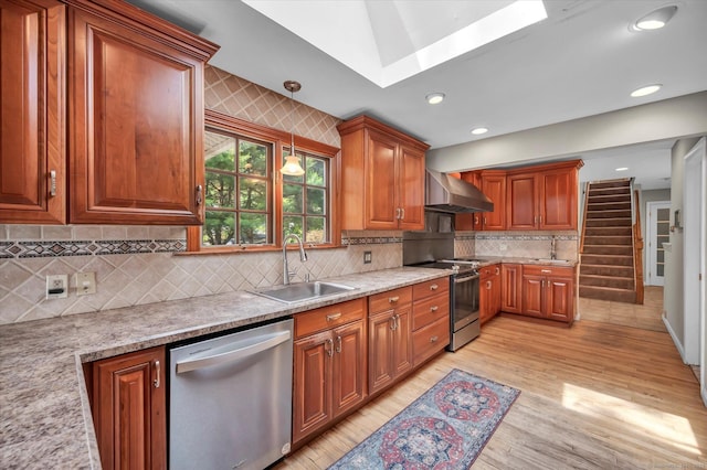 421 Hemlock Point Dr, Coventry, CT 06238 - kitchen featuring stainless steel appliances, wall chimney exhaust hood, a skylight, light wood-style floors, and brown cabinets