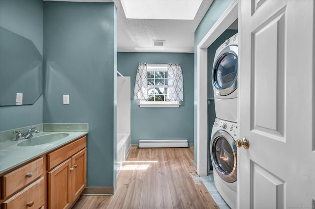 421 Hemlock Point Dr, Coventry, CT 06238 - laundry area featuring stacked washer / drying machine, baseboard heating, a skylight, light wood finished floors, and a textured ceiling