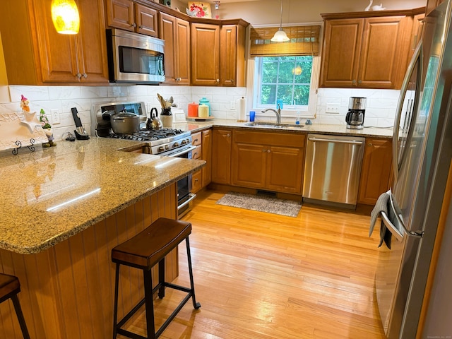 24 Alger Rd, East Haddam, CT 06423 - kitchen featuring appliances with stainless steel finishes, a peninsula, brown cabinetry, light wood finished floors, and a breakfast bar