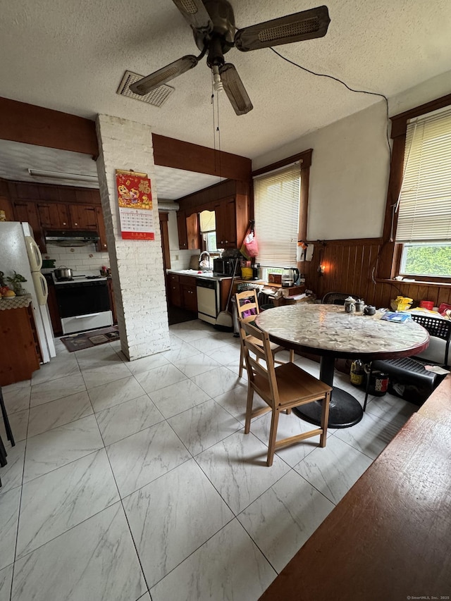 478 E Main St, Norwich, CT 06360 - dining area featuring wood walls, light marble finish floors, plenty of natural light, a ceiling fan, and a wainscoted wall