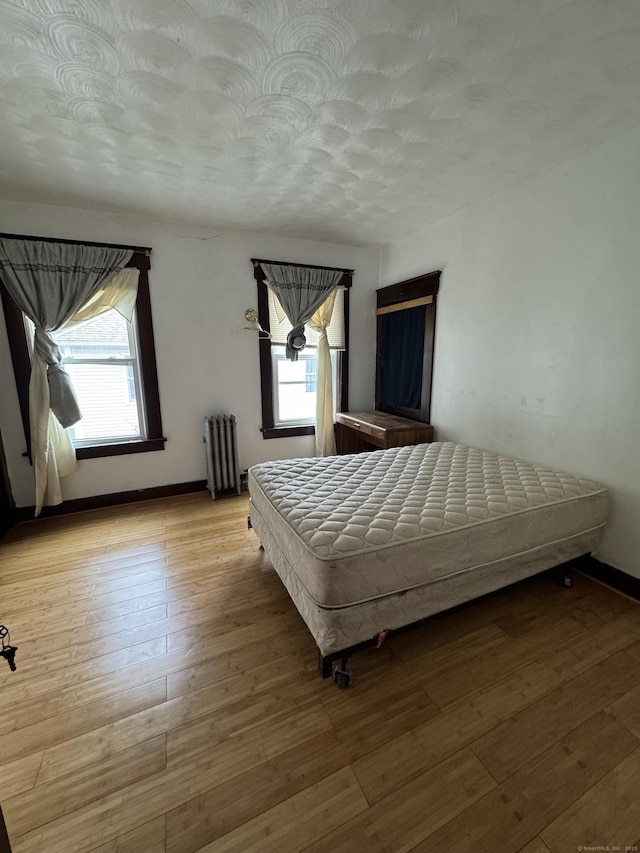 478 E Main St, Norwich, CT 06360 - bedroom featuring radiator, multiple windows, wood-type flooring, and a textured ceiling