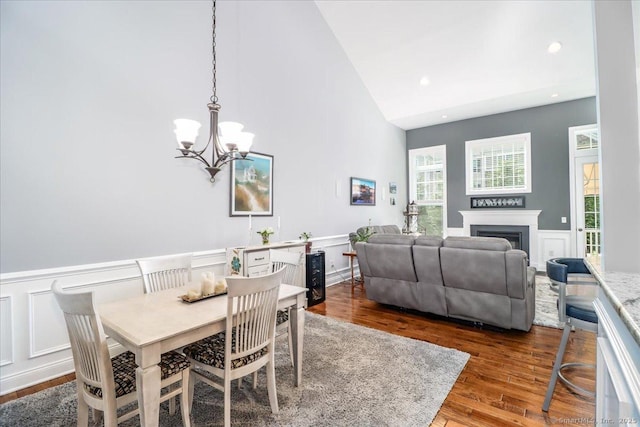 17 Brookside Ct Unit 17, Newtown, CT 06470 - dining space with a chandelier, high vaulted ceiling, a decorative wall, a fireplace, and wood finished floors