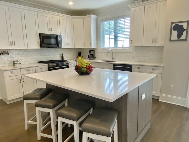 159 Colonial Rd Unit 5, Stamford, CT 06906 - kitchen featuring gas stove, white cabinets, a kitchen bar, dark wood-type flooring, and recessed lighting