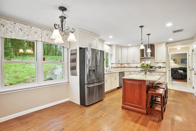 58 Inca Dr, Trumbull, CT 06611 - kitchen with appliances with stainless steel finishes, wall chimney range hood, decorative backsplash, a kitchen island, and light stone countertops