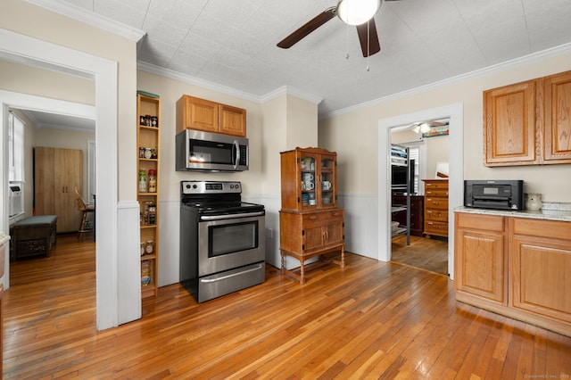89 Geer Ave, Norwich, CT 06360 - kitchen with stainless steel appliances, a ceiling fan, light wood-style floors, crown molding, and wainscoting
