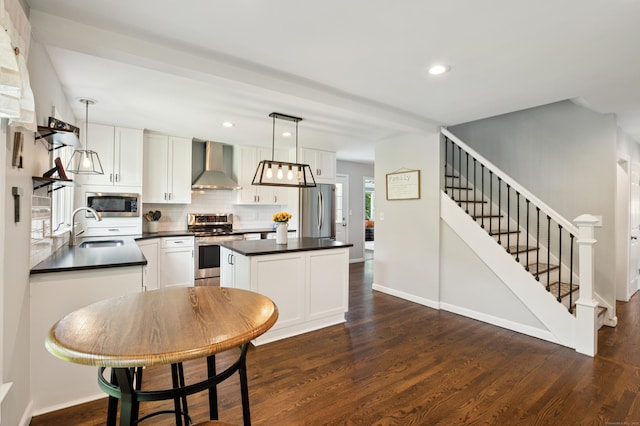 28 Saddle Ridge Dr, Simsbury, CT 06092 - kitchen with wall chimney range hood, appliances with stainless steel finishes, dark countertops, a center island, and dark wood-style flooring