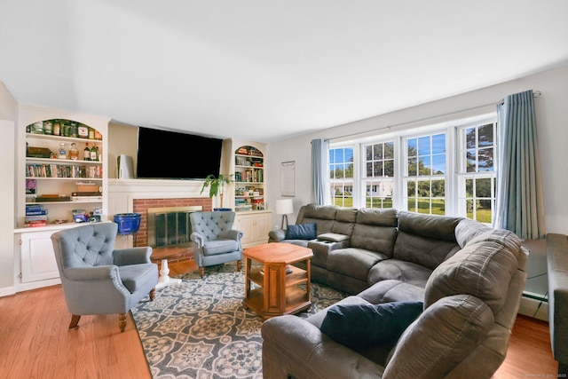 39 Alder Rd, Simsbury, CT 06070 - living area with light wood finished floors, built in shelves, a baseboard radiator, and a brick fireplace