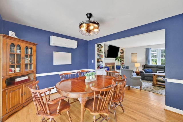 39 Alder Rd, Simsbury, CT 06070 - dining area with a wall mounted air conditioner, light wood finished floors, a fireplace, and built in shelves