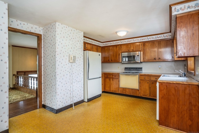 62 Eddy Ln, Newington, CT 06111 - kitchen with freestanding refrigerator, range with electric cooktop, stainless steel microwave, wallpapered walls, and brown cabinetry