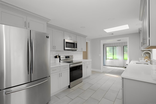 3743 Park Ave, Fairfield, CT 06825 - kitchen featuring appliances with stainless steel finishes, a skylight, light countertops, tasteful backsplash, and light tile patterned flooring