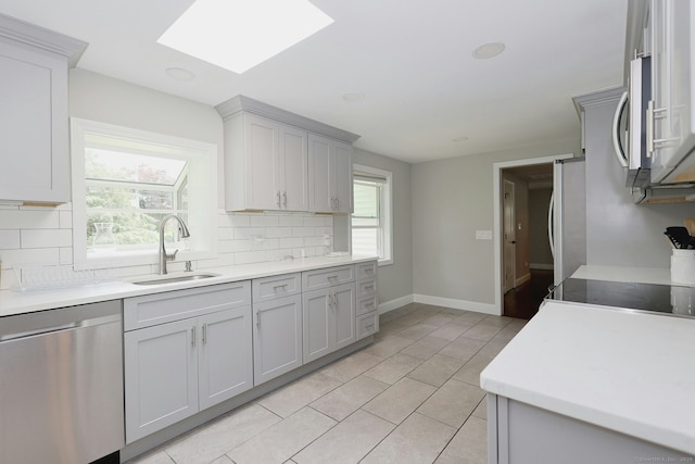 3743 Park Ave, Fairfield, CT 06825 - kitchen with appliances with stainless steel finishes, decorative backsplash, a skylight, gray cabinets, and light tile patterned floors