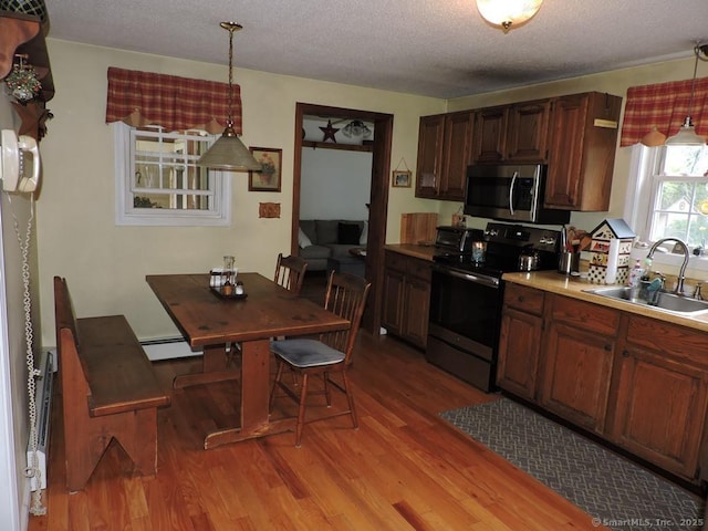 14 Cartier Rd, Enfield, CT 06082 - kitchen with appliances with stainless steel finishes, light wood-type flooring, hanging light fixtures, a textured ceiling, and a baseboard heating unit