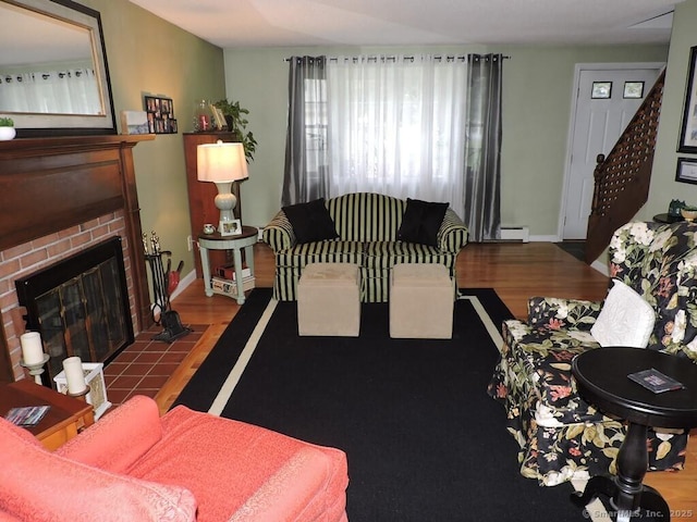 14 Cartier Rd, Enfield, CT 06082 - living room featuring wood finished floors, a baseboard radiator, a brick fireplace, and stairway