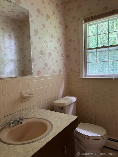 147 Beers Rd, Easton, CT 06612 - half bath with wallpapered walls, a baseboard heating unit, vanity, tile walls, and a wainscoted wall