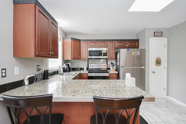 31 Bristol St, Thomaston, CT 06787 - kitchen with stainless steel appliances, a peninsula, a kitchen bar, light marble finish flooring, and a skylight